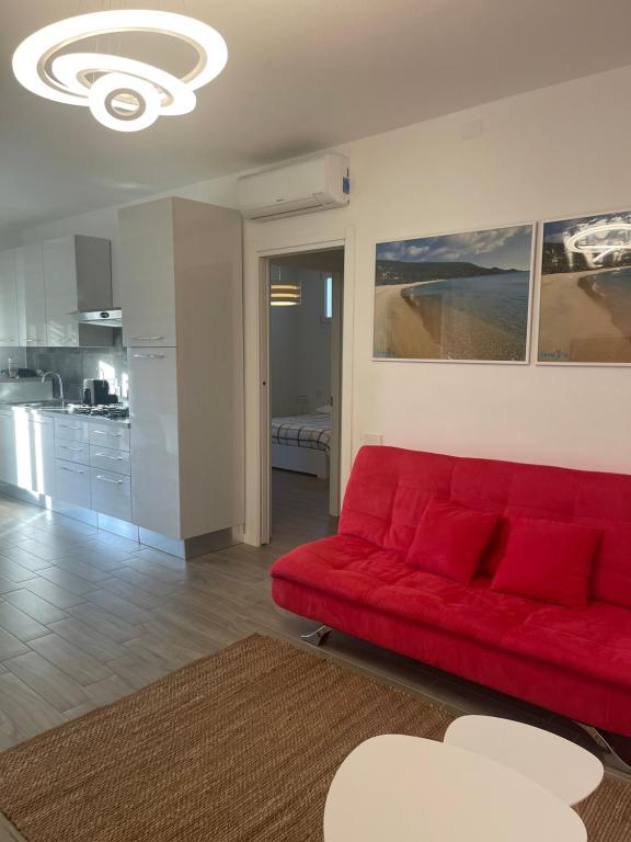 a red couch in a living room with a kitchen at Residenza Tramontana in Elmas
