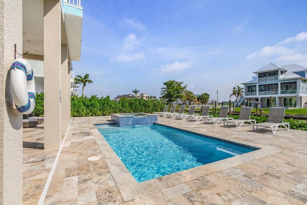 una piscina con sillas y una casa en 671 Estero Blvd "Ocean Pearl" home, en Fort Myers Beach