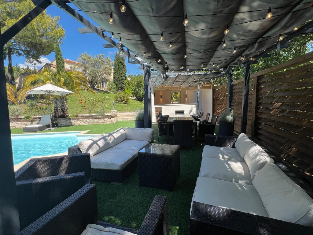 un patio con sofás y una piscina en Le Mas de l'Alliance - 12 p - Air Cond - private Pool - near Grignan en Roussas