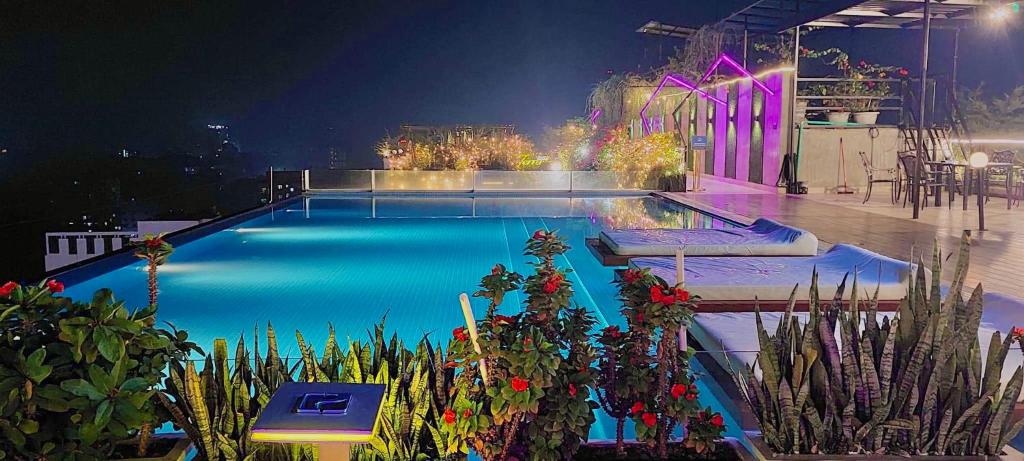 una piscina por la noche con plantas y luces en Hotel Noorjahan Grand, en Sylhet