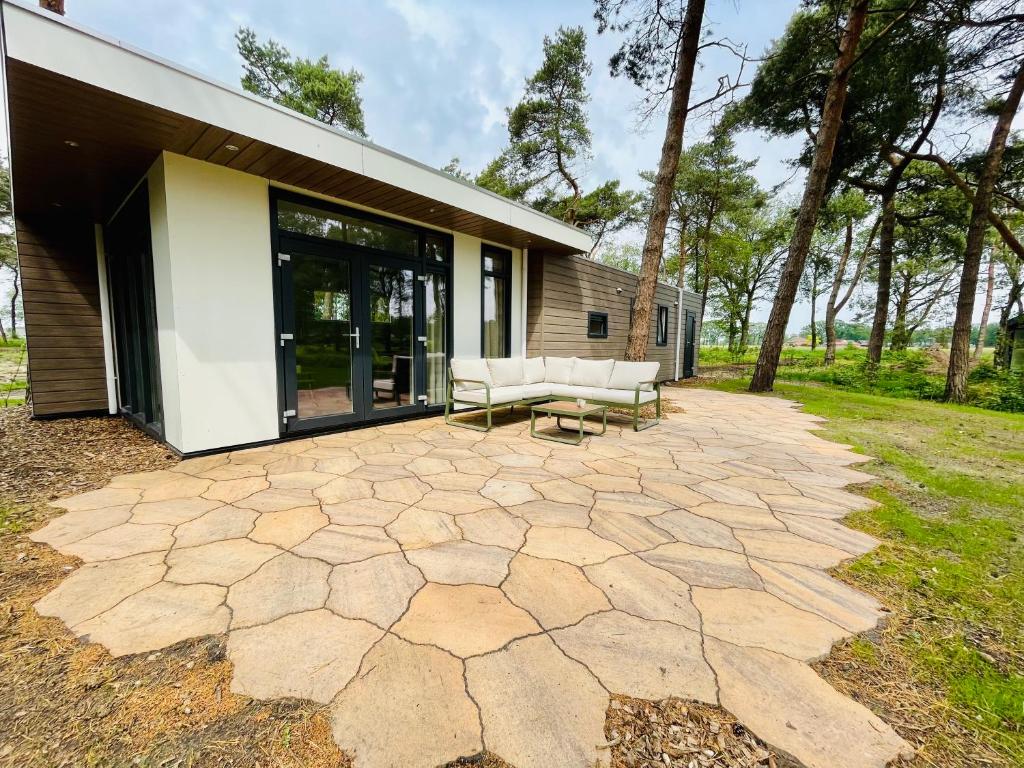 Un patio con dos sillas blancas y un edificio. en Ferny Cabin, en Haarle