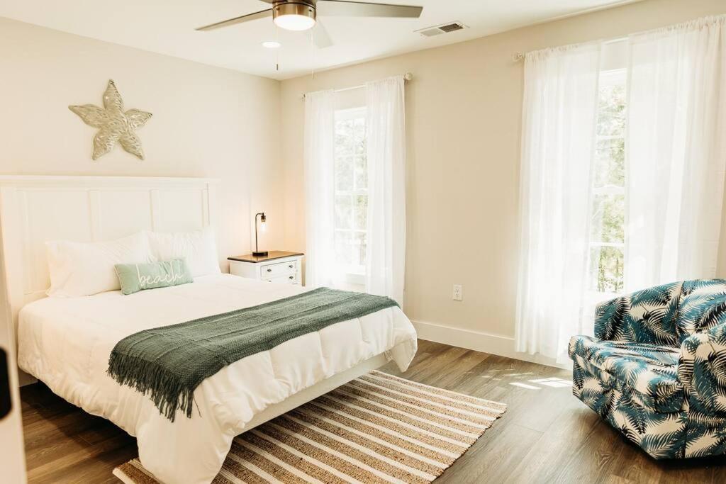 a white bedroom with a bed and a chair at Dreamy Palms in Myrtle Beach