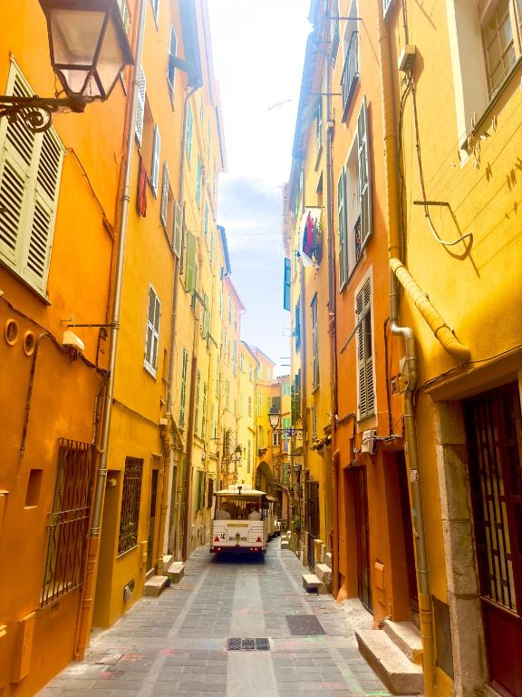 une camionnette roulant dans une rue avec des bâtiments jaunes dans l'établissement Menton Old Town, à Menton
