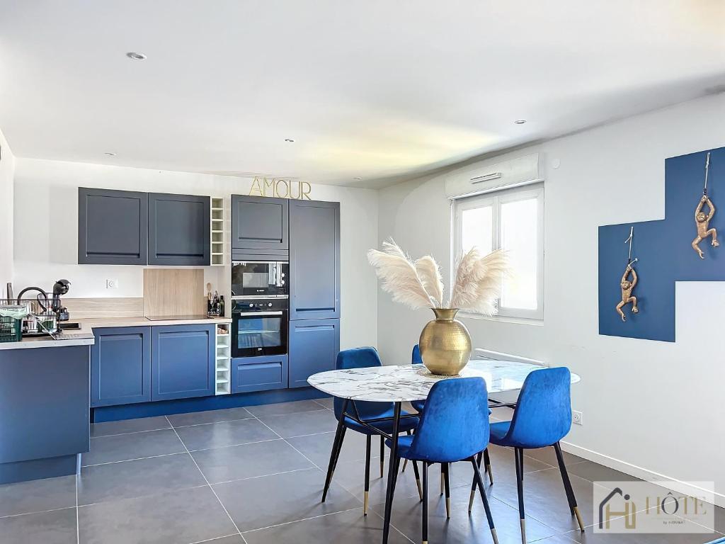 una cucina con armadi blu e un tavolo con sedie blu di Appartement « Marine Serenity » - 50m de la plage a Bray-Dunes