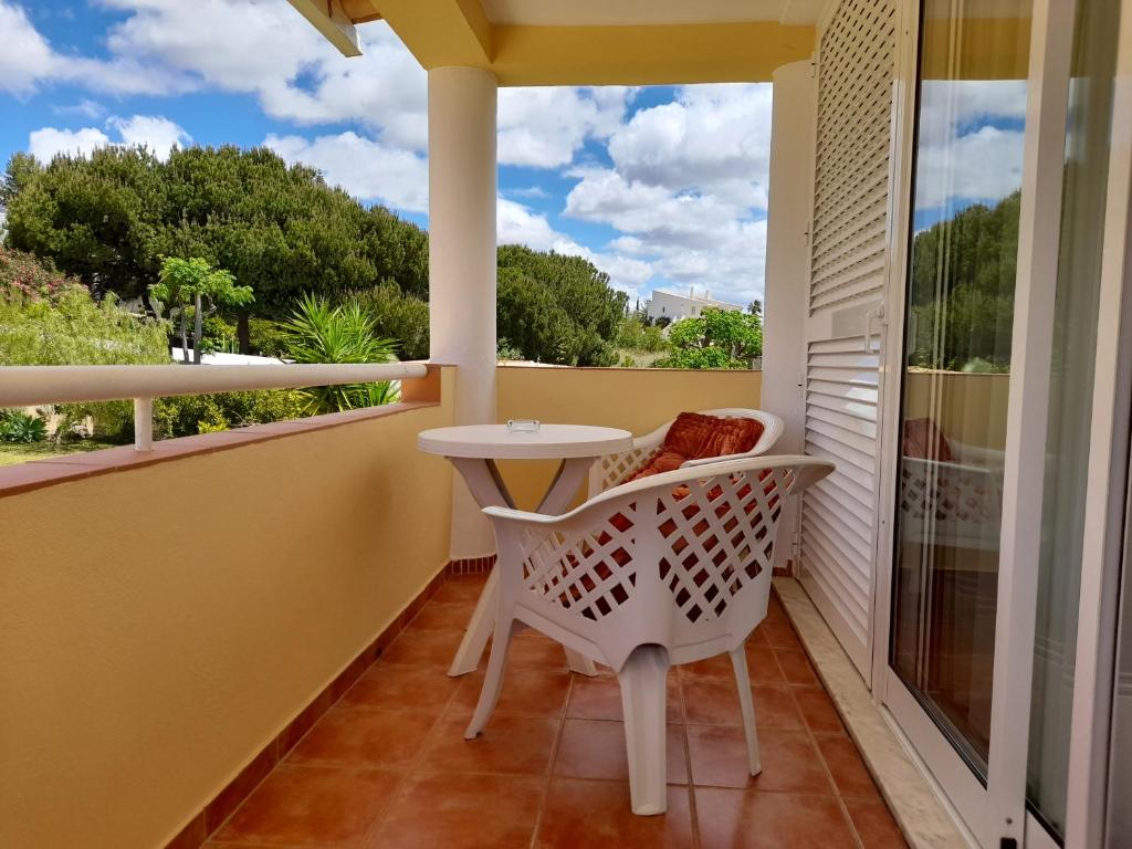 a balcony with a white table and chairs and a window at Aurora Sol in Luz