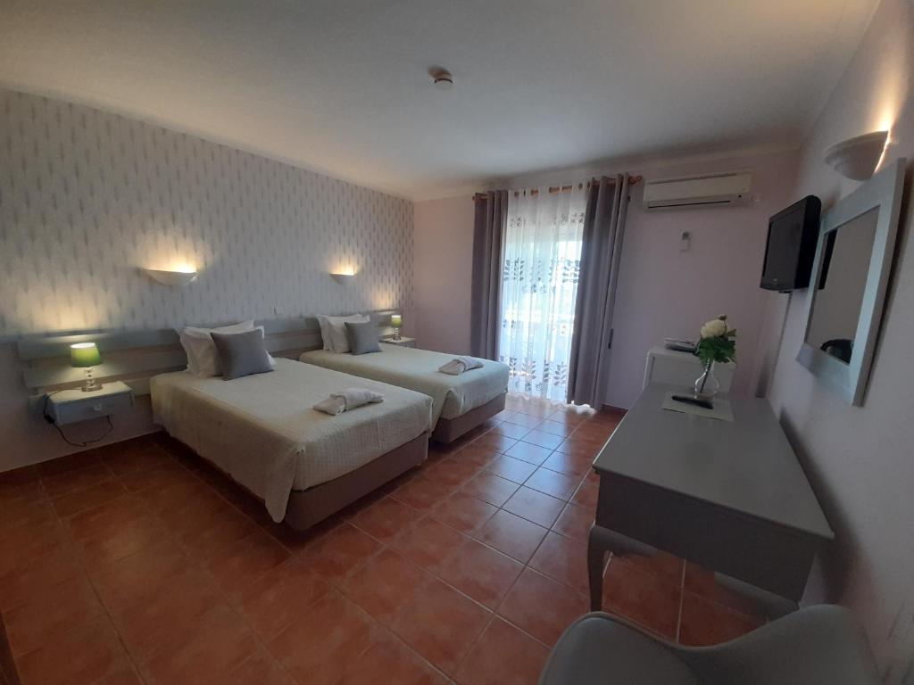 a hotel room with two beds and a desk at Aurora Sol in Luz