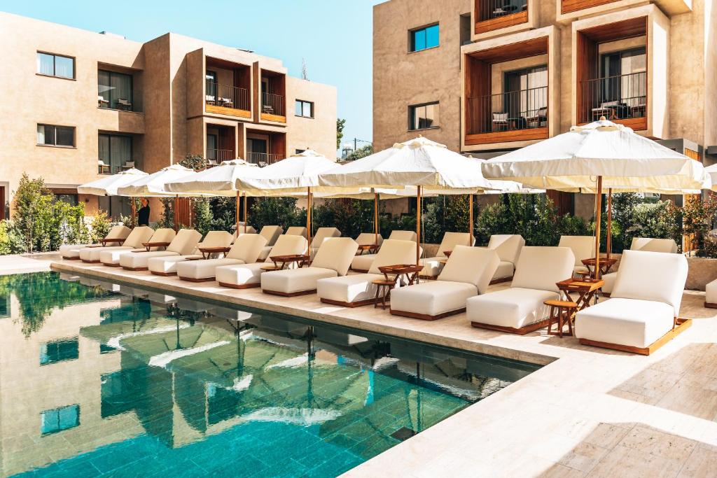 a pool with chairs and umbrellas next to some buildings at M Boutique Hotel - Designed for Adults in Paphos City