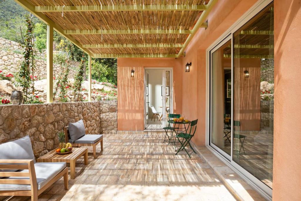 a patio with chairs and a stone wall at The OliveStone Village - Yoga Retreat Paradise in Ágios Márkos