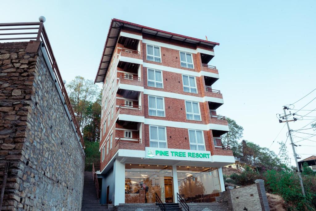 a tall red brick building with a me tree review sign on it at Pine Tree Resort in Nagarkot