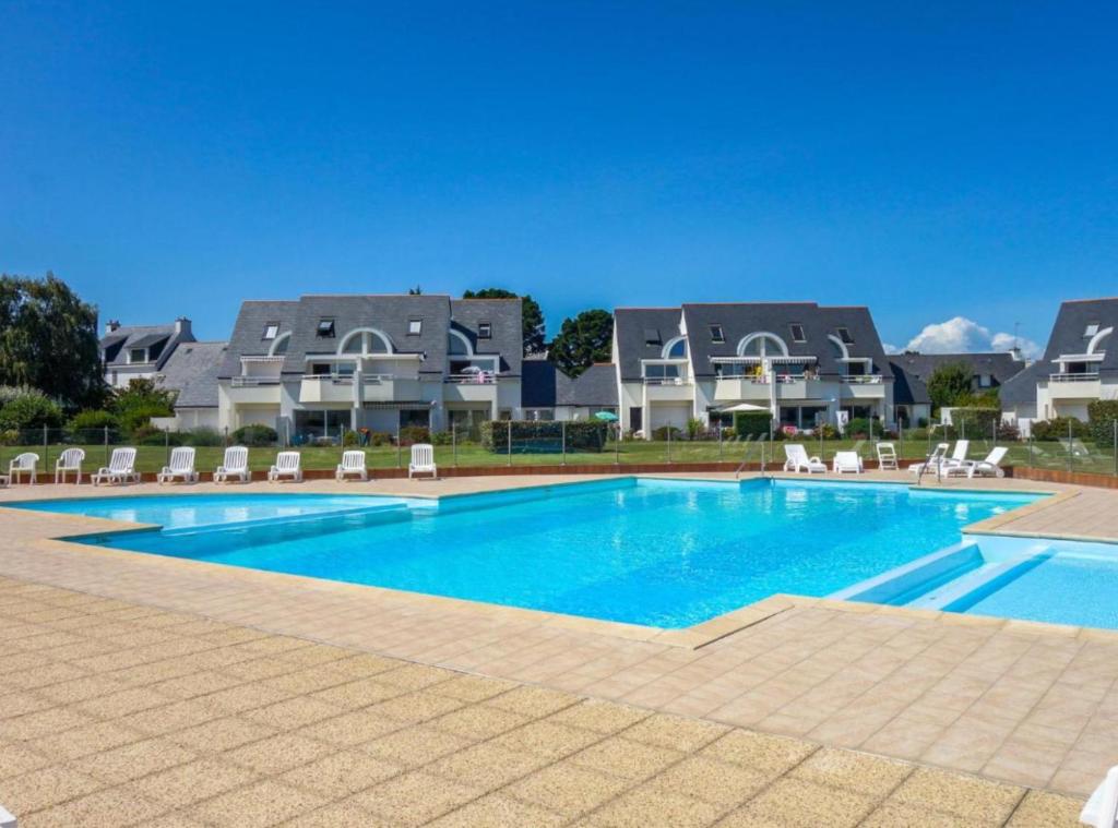 une piscine avec des chaises et une maison en arrière-plan dans l'établissement Appartement avec piscine proche thalasso et plages, à Carnac