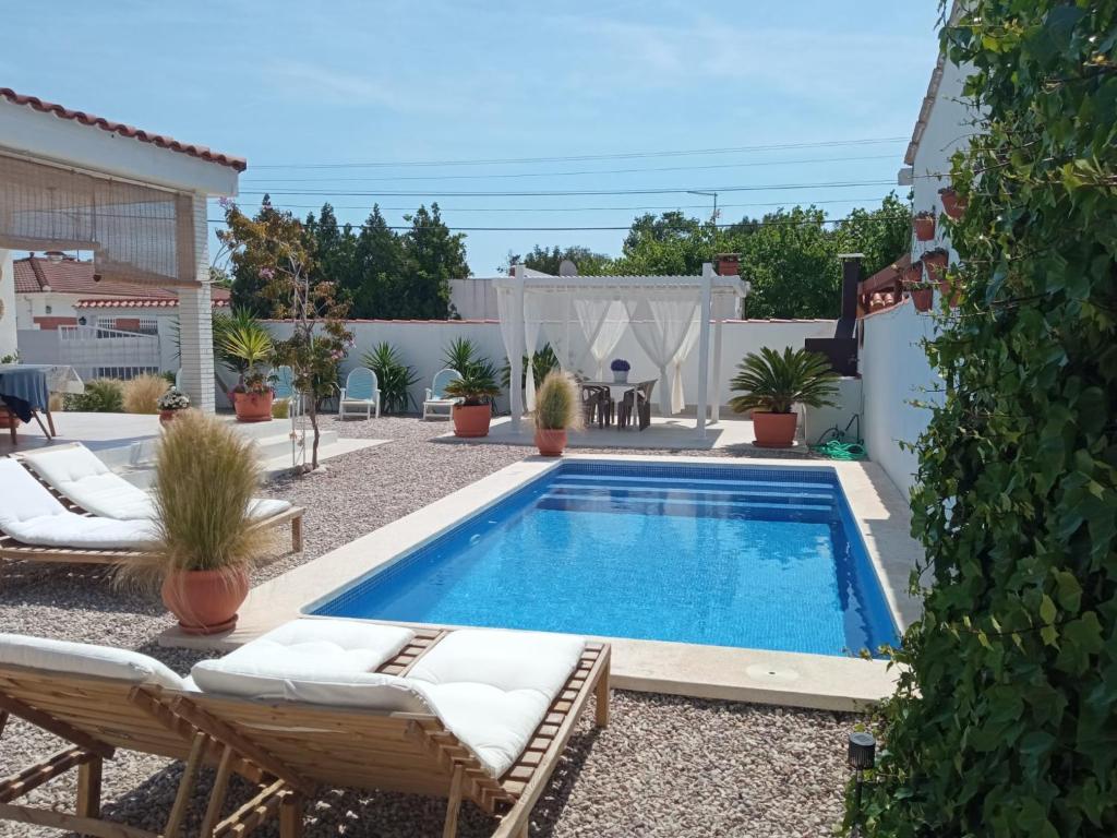 una piscina en un patio con 2 sillas de césped en Villa Ana en Vinarós