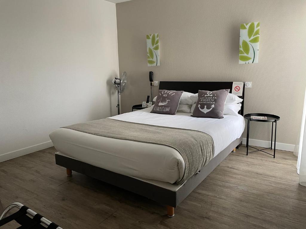 una camera da letto con un grande letto con due cuscini di Cit'Hotel Le Chêne Vert a Les Sables-dʼOlonne