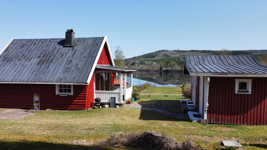 dos edificios rojos y blancos junto a un lago en Ferienhaus am See (Rådasjön), en Råda