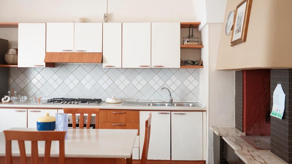 una cocina con armarios blancos y una mesa con sillas. en Casa vacanze San Cassiano Salento, en San Cassiano