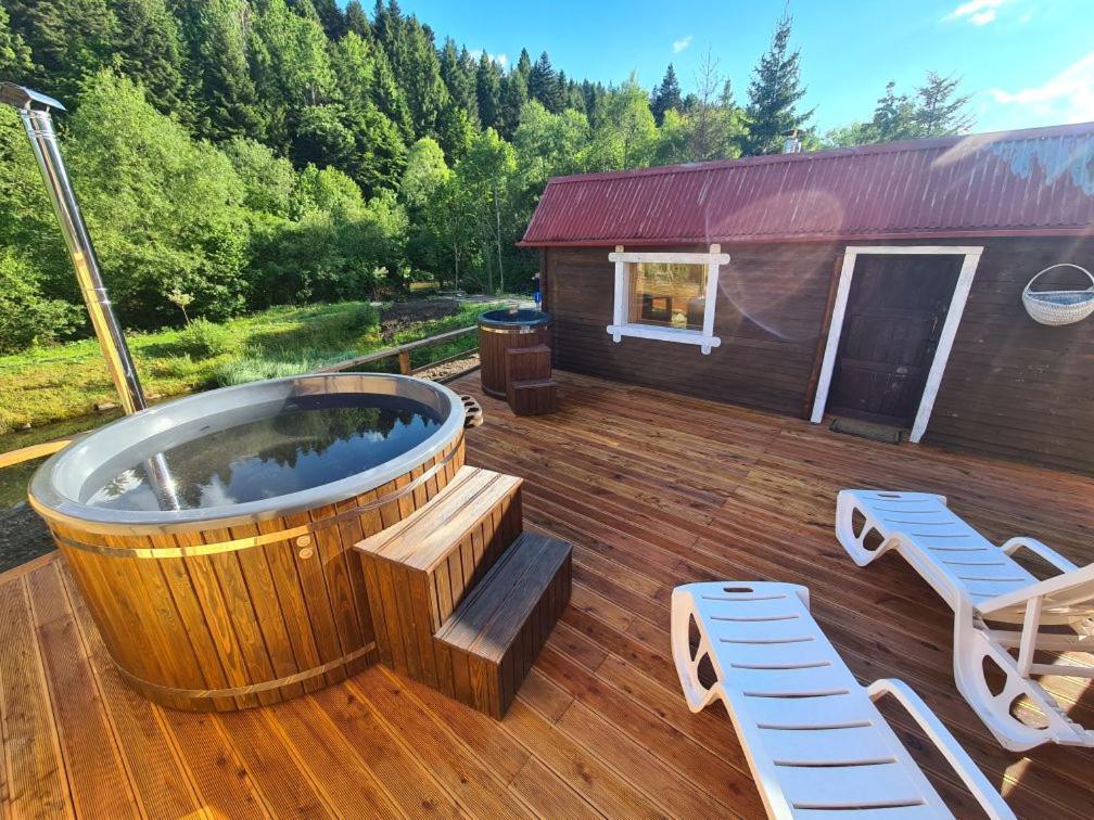 齊斯的住宿－Lawendowy Staw，一个带热水浴缸和两把椅子的大型木制甲板
