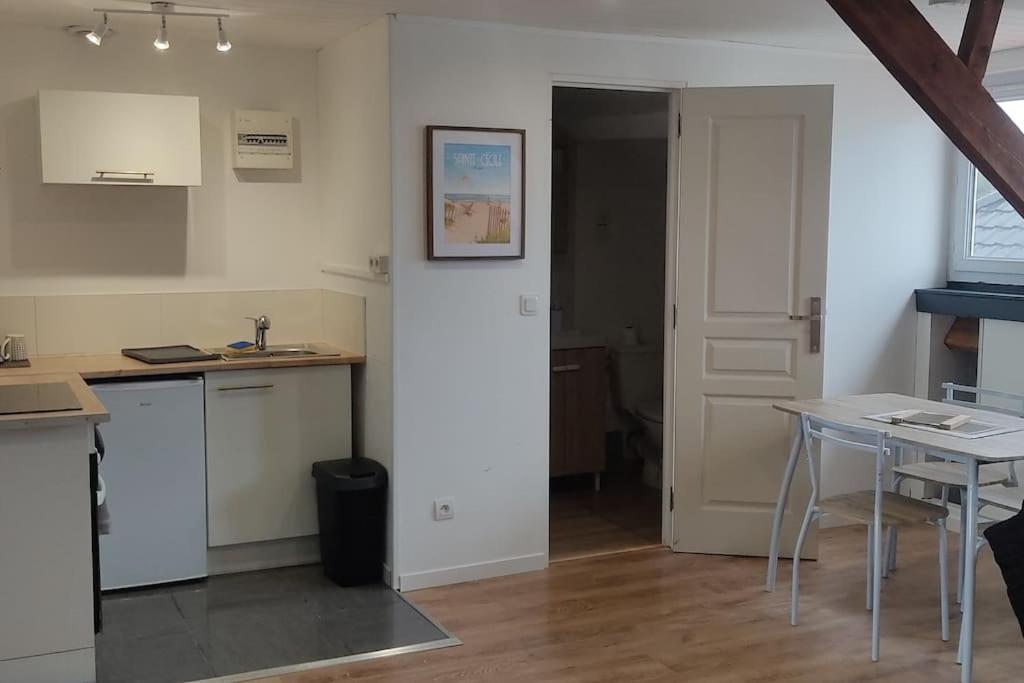 Cette chambre comprend une cuisine avec une table et une porte. dans l'établissement Appartement à 300m de la plage avec parking privé, à Camiers