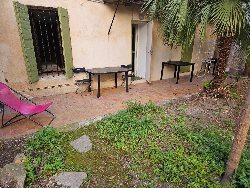 un patio avec deux tables et une chaise rose dans l'établissement Logement avec jardin gare St Charles, à Marseille