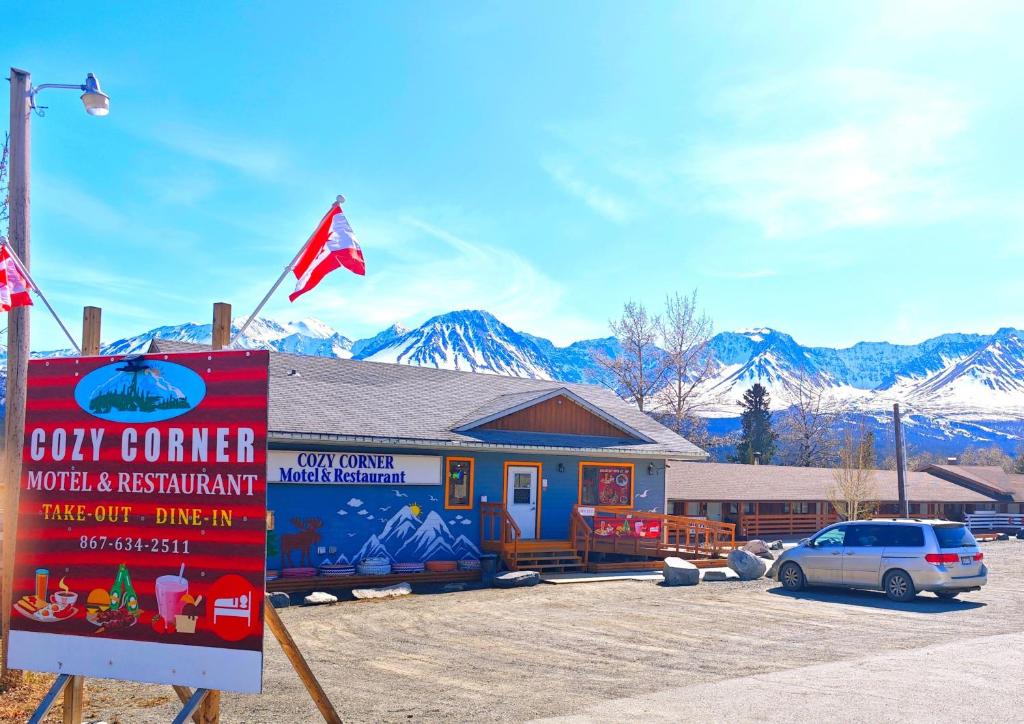 un coche aparcado frente a un edificio con bandera en Cozy Corner Motel & Restaurant en Haines Junction