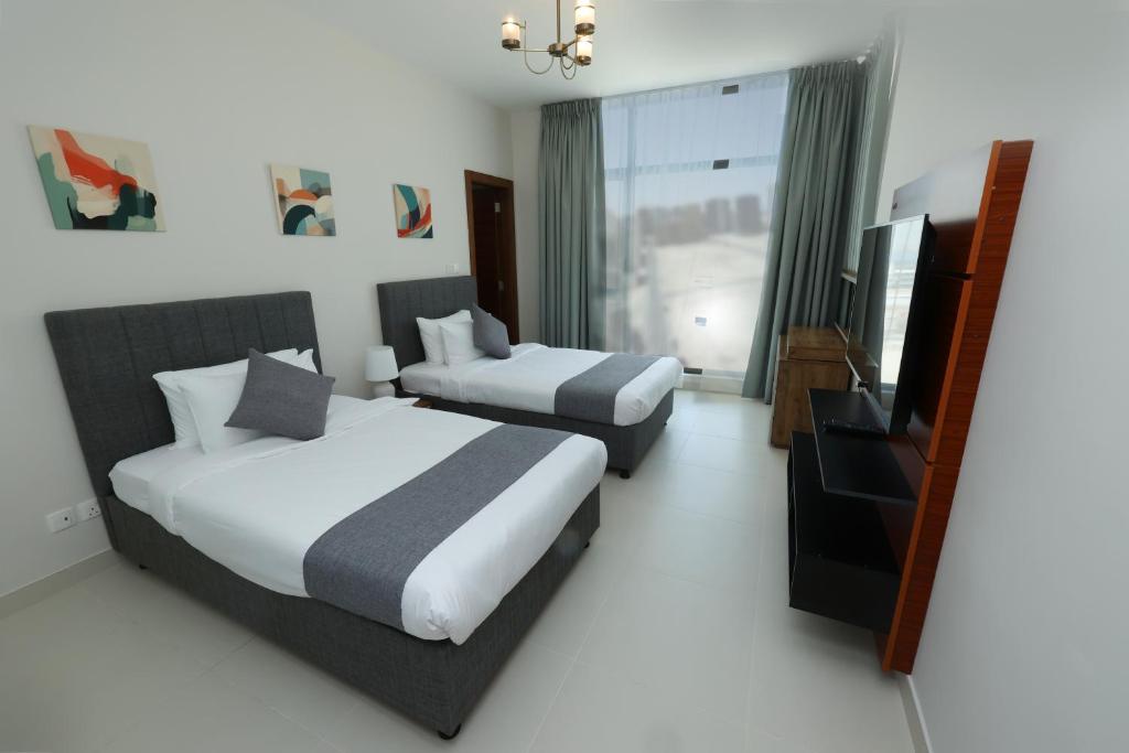 Habitación de hotel con 2 camas y TV de pantalla plana. en Noor Amwaj Hotel & Apartment en Manama