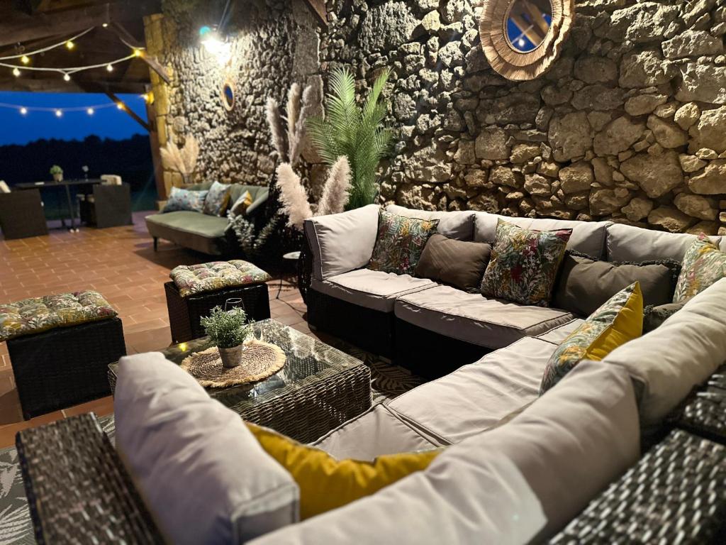 a living room with couches and a stone wall at Gites Boutique in Villamblard