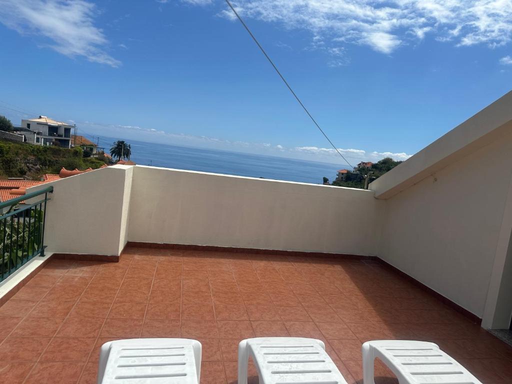 un balcón con 2 sillas blancas y el océano en Elisabeth House, en Ponta do Sol