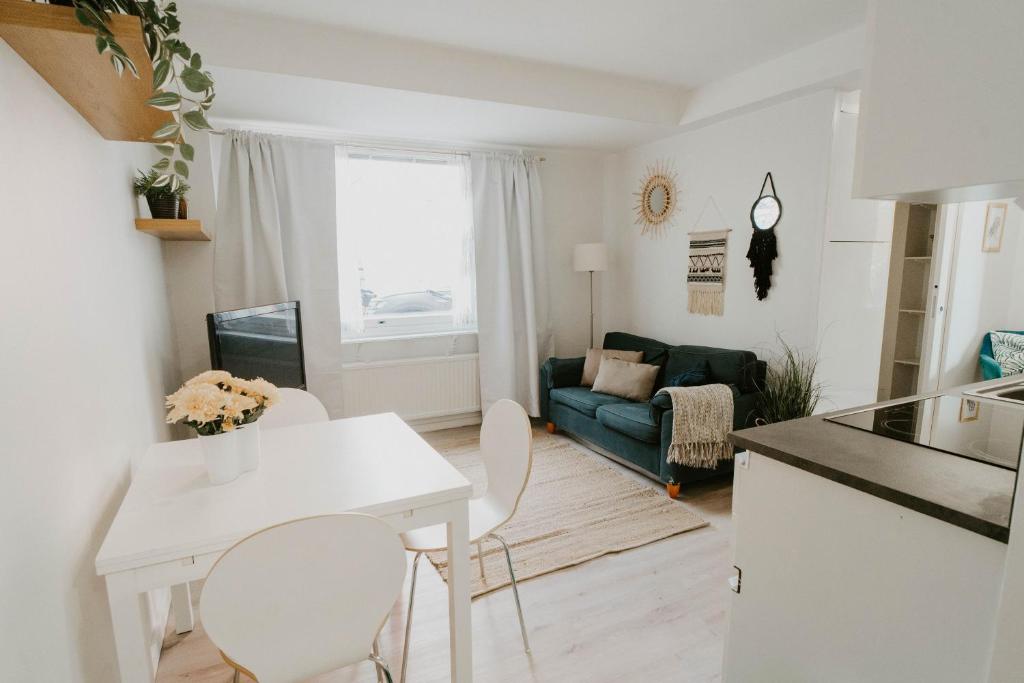 Il dispose d'une cuisine et d'un salon avec une table et des chaises blanches. dans l'établissement ~ A modern flat at a calm ground floor ~, à Espoo
