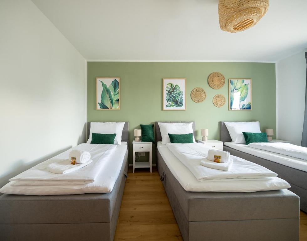 two beds in a room with green walls at C4S -COME4STAY- Stilvoll eingerichtetes Apartment für bis zu 8 Personen - Hochwertige Betten I voll ausgestattete Küche I Balkon I Badezimmer I WLAN I Smart TV in Töging am Inn