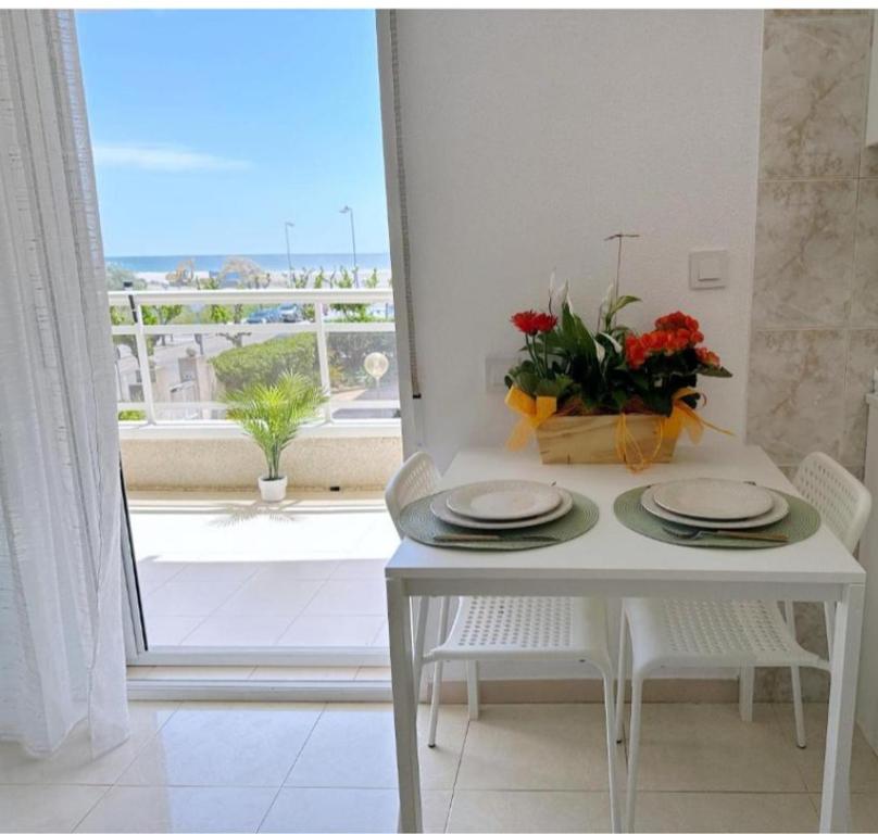 a white table with two plates and a vase of flowers at AT-Pineda-03 in La Pineda