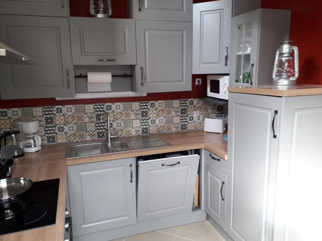 une cuisine avec des armoires blanches et un évier dans l'établissement La luzerne, à Saint-Martin-le-Hébert