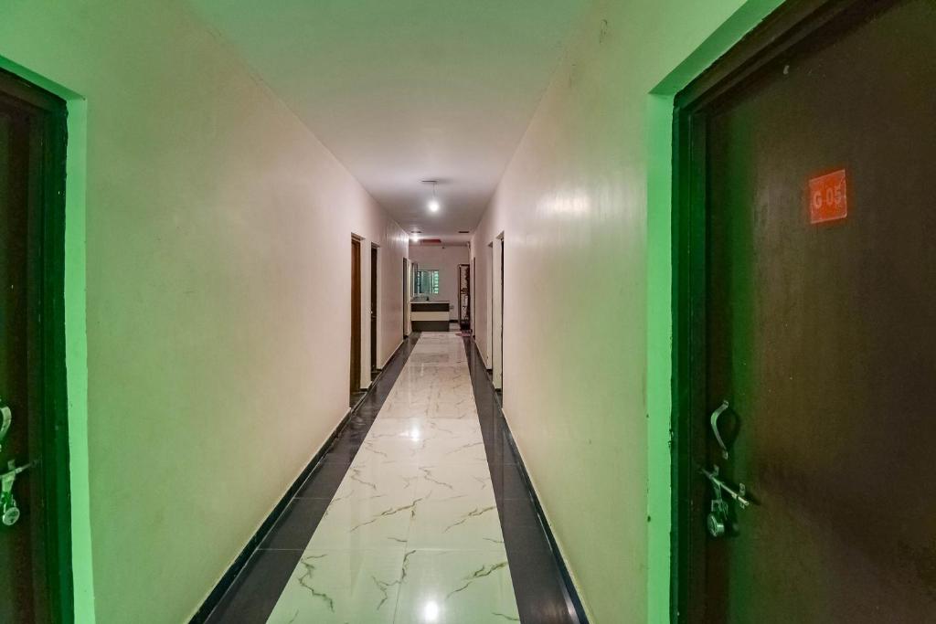 un couloir vide avec des murs verts et un couloir avec des portes dans l'établissement SPOT ON 66974 Hotel shri gurukripa, à Gwalior