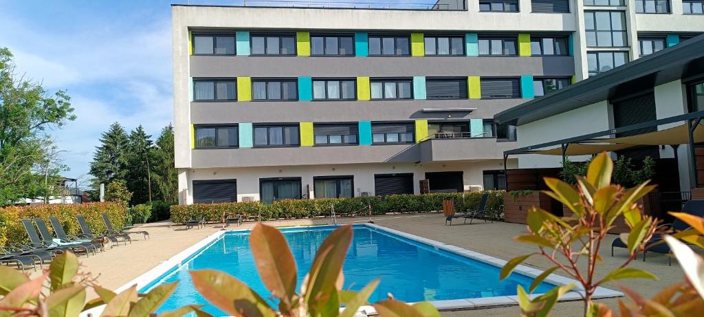 a building with a swimming pool in front of a building at Éden apartman in Balatonföldvár