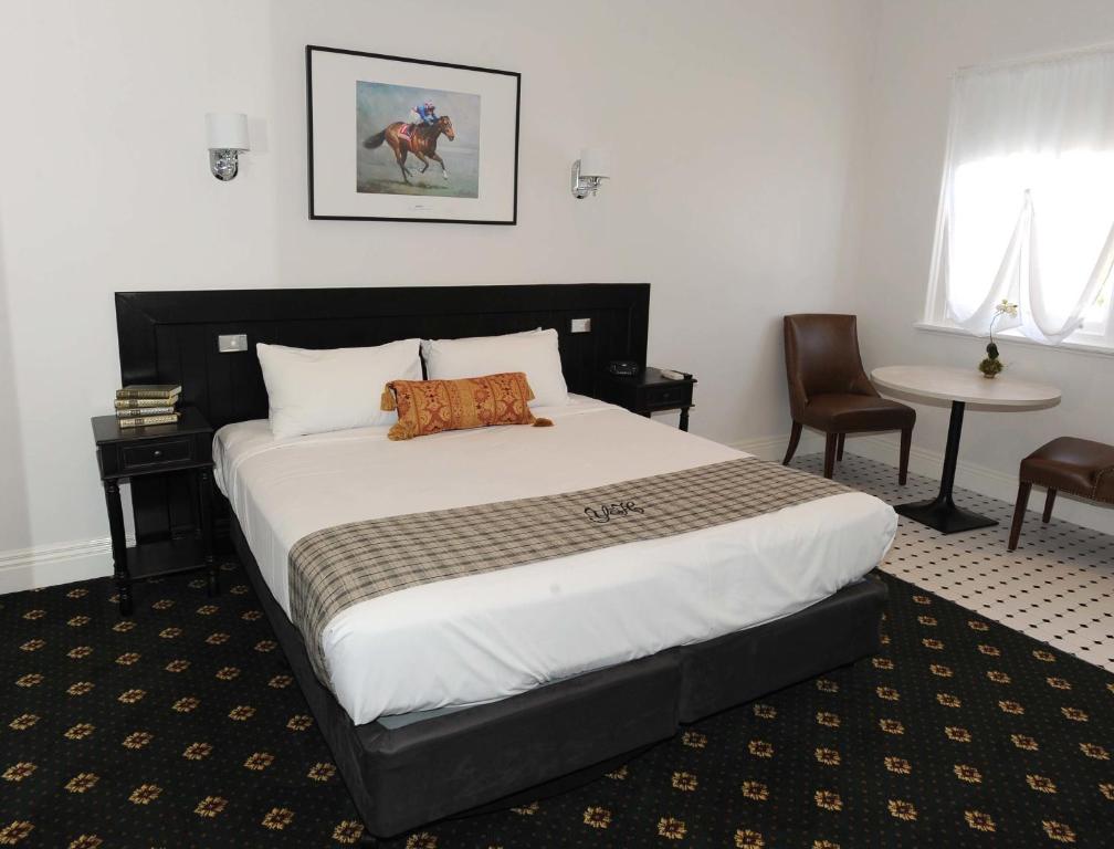 a bedroom with a large bed and a table and chairs at The Yarrawonga Hotel in Yarrawonga