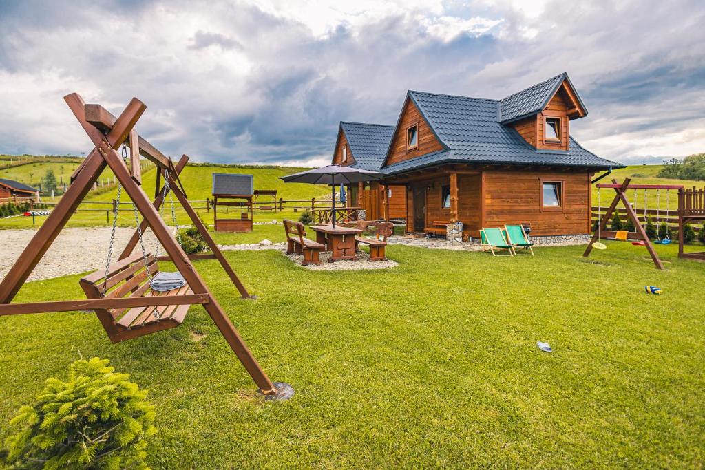 une cabane en rondins avec une aire de jeux dans la cour dans l'établissement Domek na Leśnej, à Łapsze Niżne