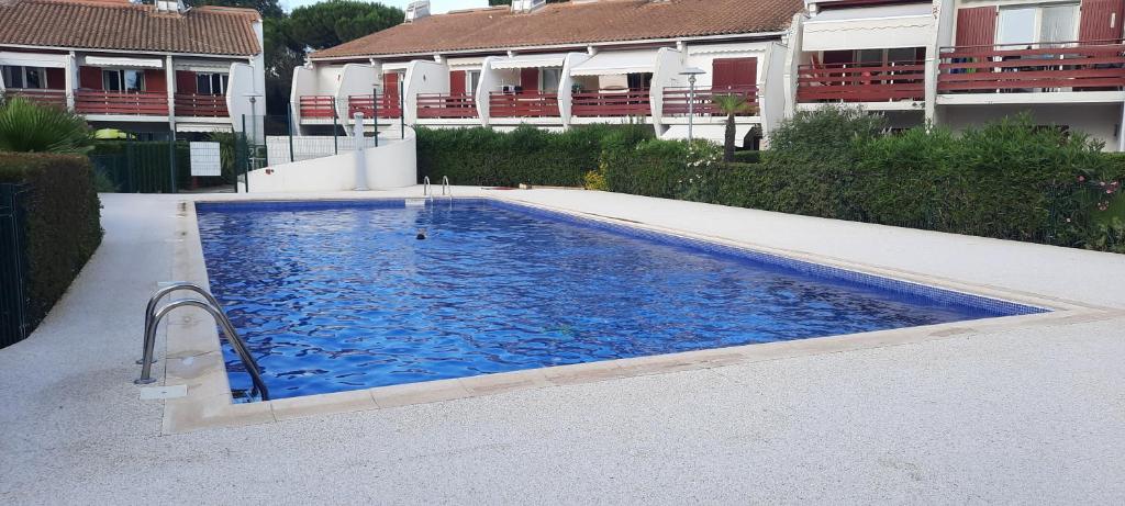 une grande piscine bleue en face de certains bâtiments dans l'établissement Green Village - Entre nature et mer, à La Grande Motte
