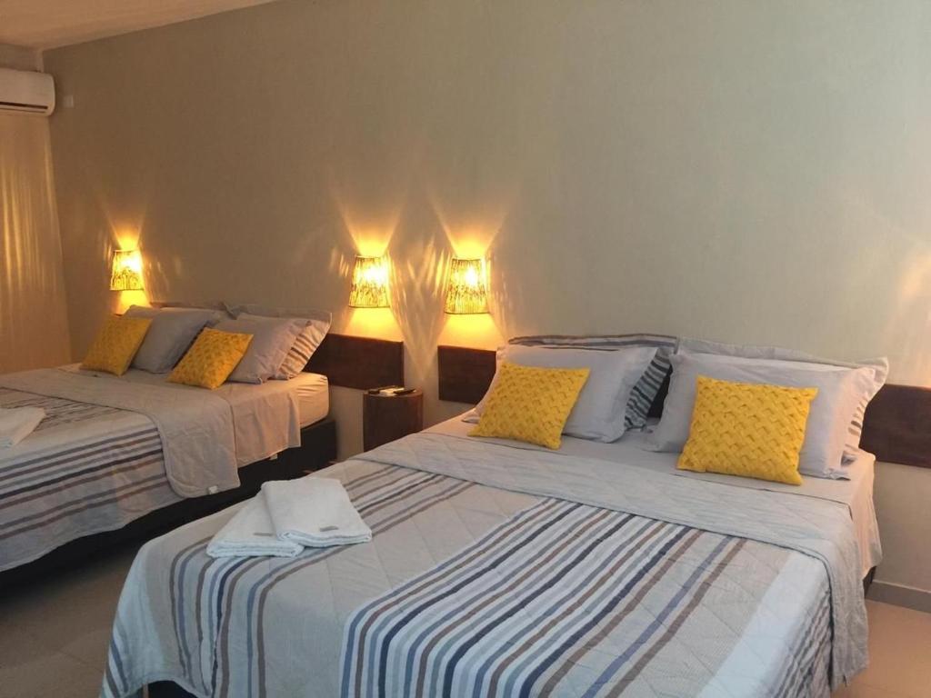 um quarto com 2 camas e almofadas amarelas em Pousada das Palmeiras em Salinópolis