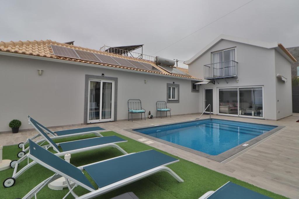 a villa with a swimming pool and two chairs at Vila Castro in Estreito da Calheta