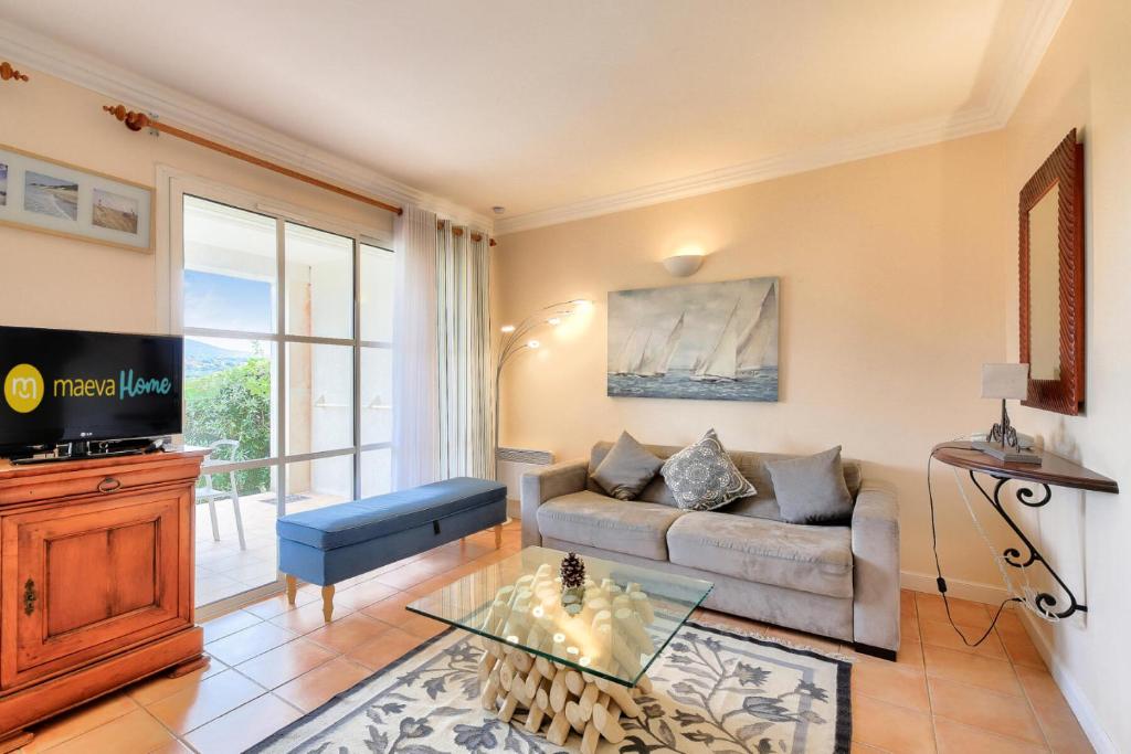un salon avec un canapé et une télévision dans l'établissement Les Villas aux Restanques du Golfe de St Tropez - maeva Home - Villa vue colline 3 pièces 6 personnes - Prestige MAE-8591, à Grimaud