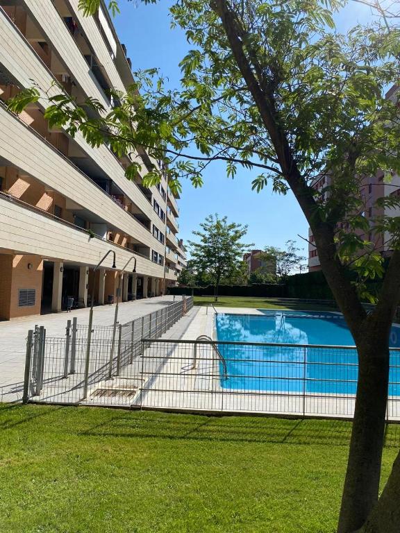 a fence around a swimming pool next to a building at Camino Santiago Naturaleza en Logroño Parking y Piscina by Apartamentos Logrono org in Logroño