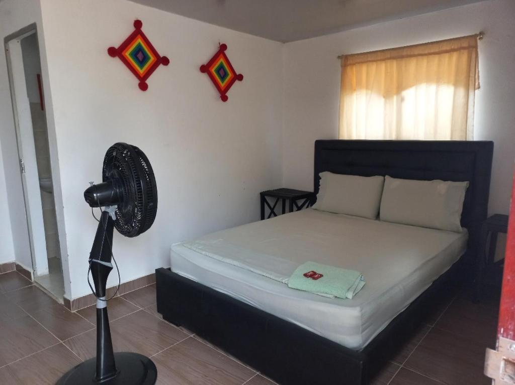 a bedroom with a bed with a fan and a window at PLAYA ARCO IRIS in Cabo de la Vela
