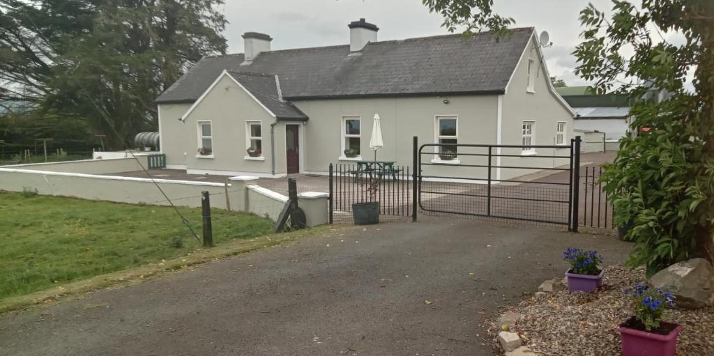 a white house with a gate and a driveway at Birdhill Farmhouse in Tipperary