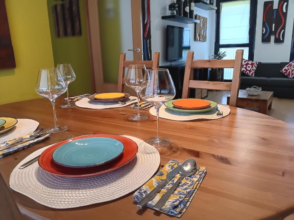 a wooden table with plates and wine glasses on it at Camino Santiago Etxea in Jaca