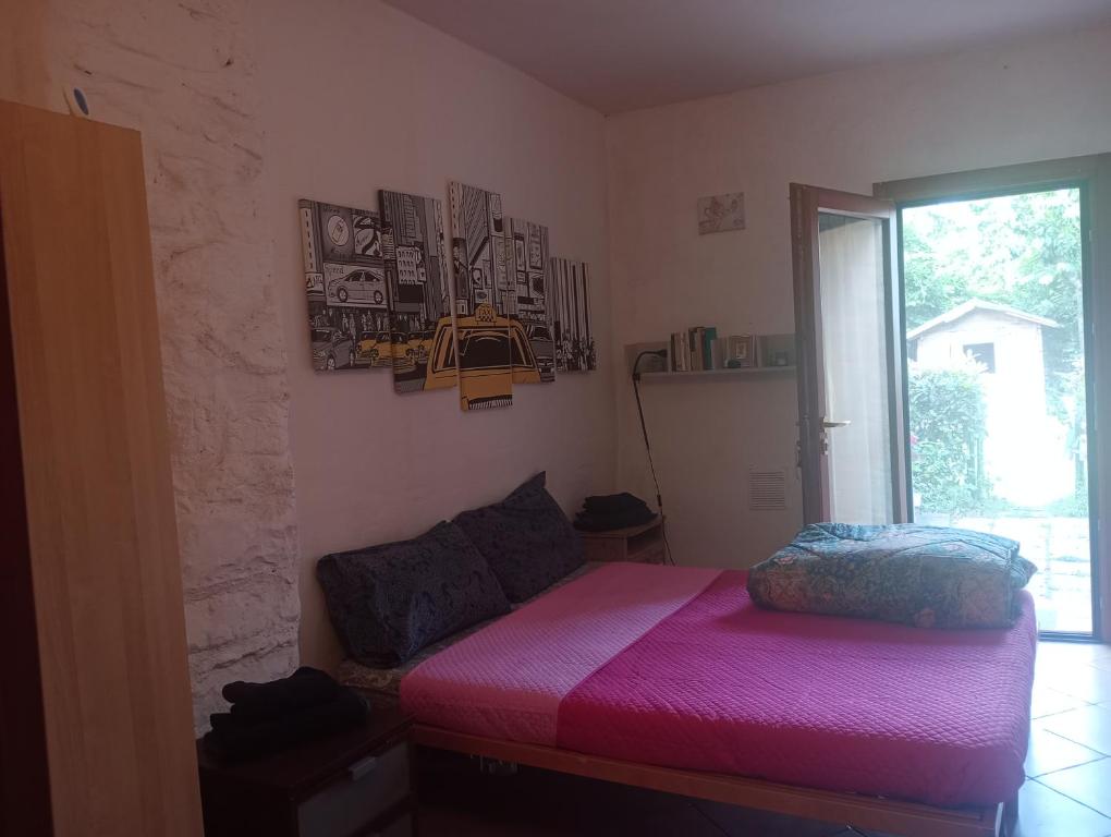 a bedroom with a pink bed and a window at Casa di Penna in Barberino di Mugello