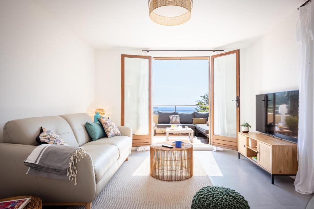un salon avec un canapé et une télévision dans l'établissement GOODLIFEPRAMOUSQUIER classe 3 etoiles Appartement 2 ch, belle vue mer et nature, calme et plage à pied, au Lavandou