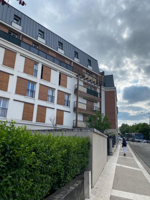 una persona che cammina lungo un marciapiede di fronte a un edificio di Tranquillité à 30 min de Paris a Poissy