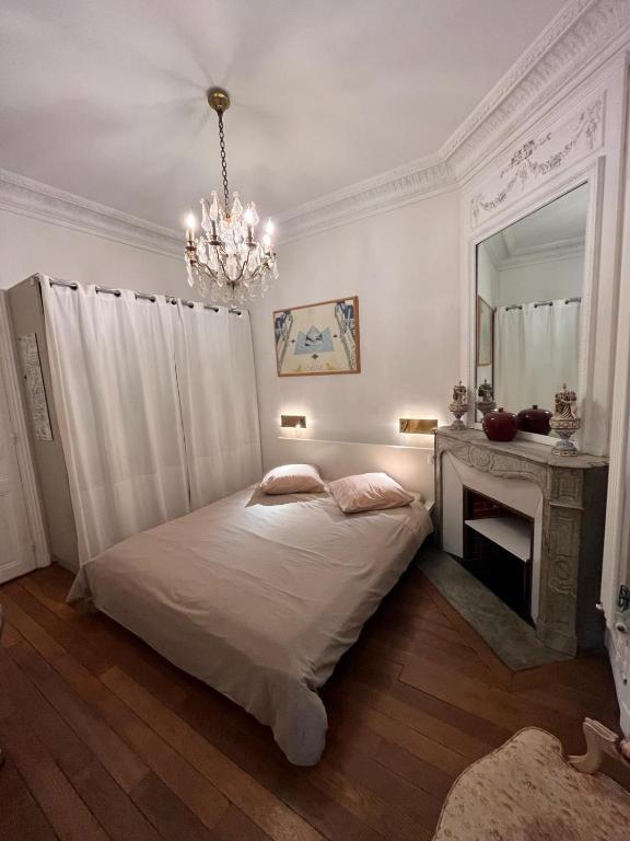 - une chambre avec un lit, un miroir et un lustre dans l'établissement Grande chambre privée sur jardin arboré, à Paris