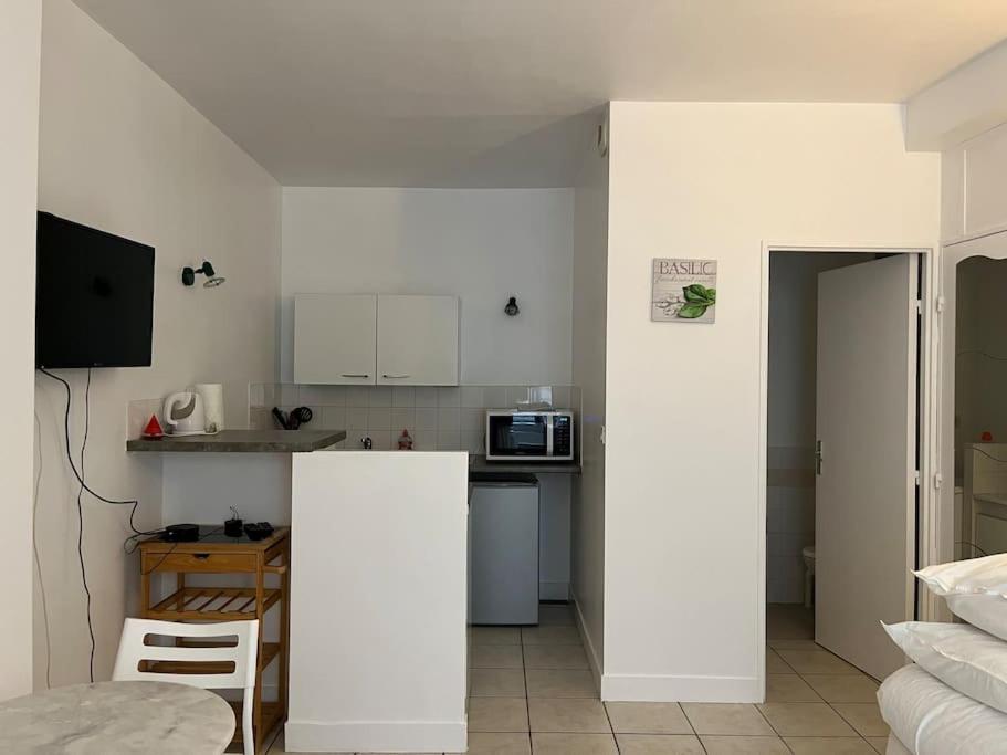 une petite cuisine avec des armoires blanches et une table dans l'établissement Studio 8 - Bord de Loire, à Orléans
