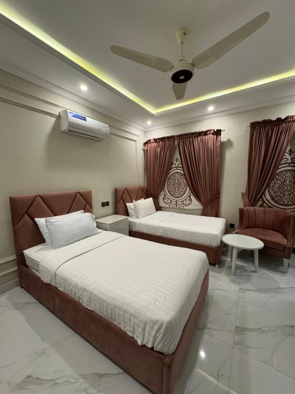 a hotel room with two beds and a chair at Emerald Villa 2 in Islamabad