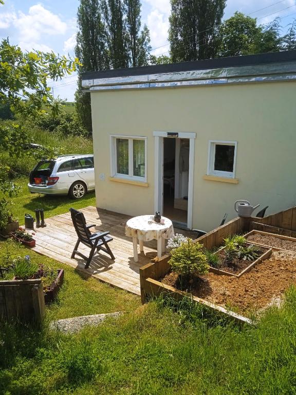 Cette petite maison blanche dispose d'une table et d'une terrasse. dans l'établissement La petite maison au calme dans les champs, à Matton-et-Clémency