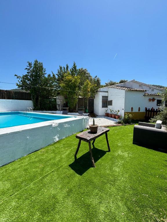 a small table in the grass next to a swimming pool at Huerta Del Pasil (Casa Entera) in Córdoba