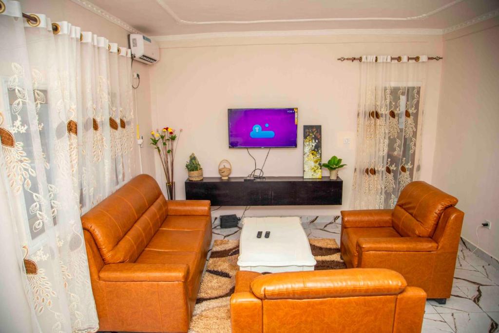 sala de estar con 2 sofás de cuero y TV en LES LOGIS DE NOUVELLE ROUTE BASTOS en Yaundé